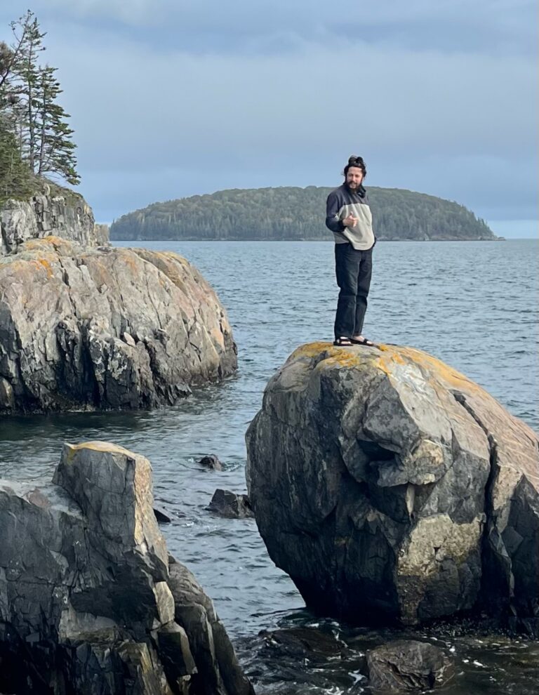 person standing on a big rock near the ocean