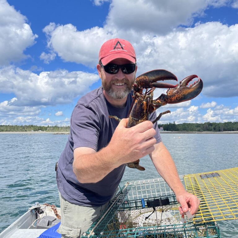 jon mitchell holding a lobster near the ocean