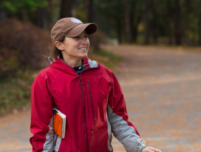 sarah holding books with ball cap on, outside