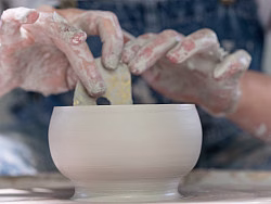 Hands shaping pottery on wheel