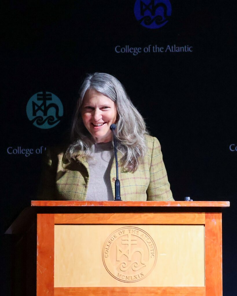 Woman speaking at podium, smiling.